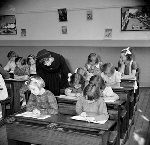 823253 Afbeelding van een groep leerlingen en een toekijkende Zuster Augustinesse in een klaslokaal op de Piusschool ...